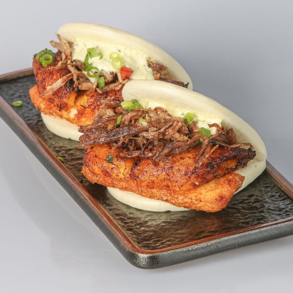 Two Bocas House bao buns filled with crispy fried chicken, shredded meat, and green onions.