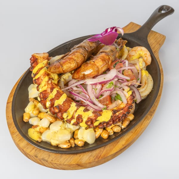 Bocas House's grilled octopus and shrimp with corn, onions, and tomatoes in a skillet.