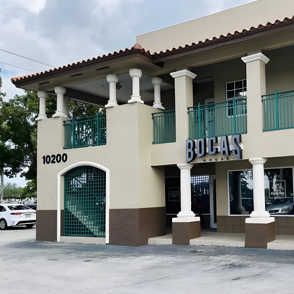 Exterior of Bocas House, a two-story building with columns, teal railings, and a prominent sign.