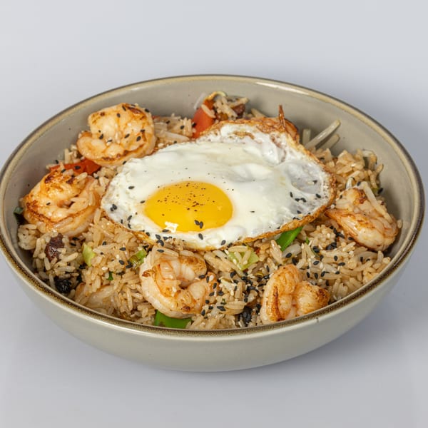 Bocas House shrimp fried rice with a sunny-side-up egg and sesame seeds in a bowl.
