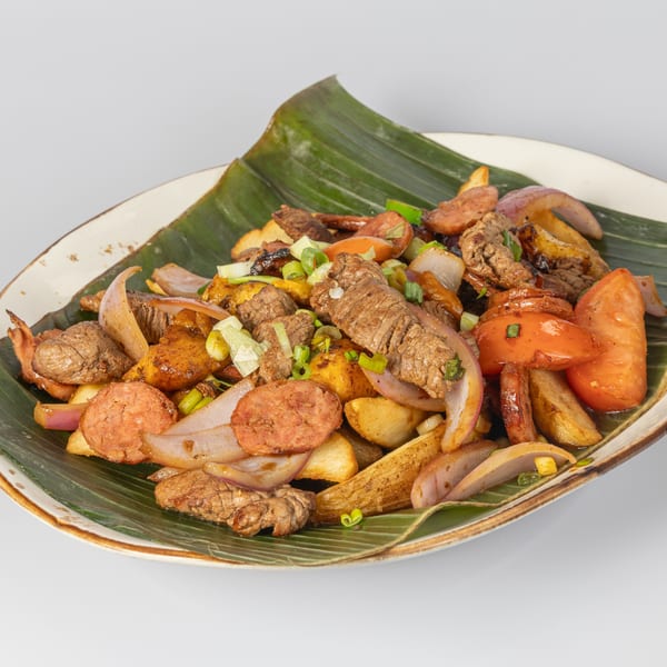 Bocas House's Lomo Saltado, a Latin-American dish with beef, sausage, potatoes, tomatoes, and onions on a banana leaf.