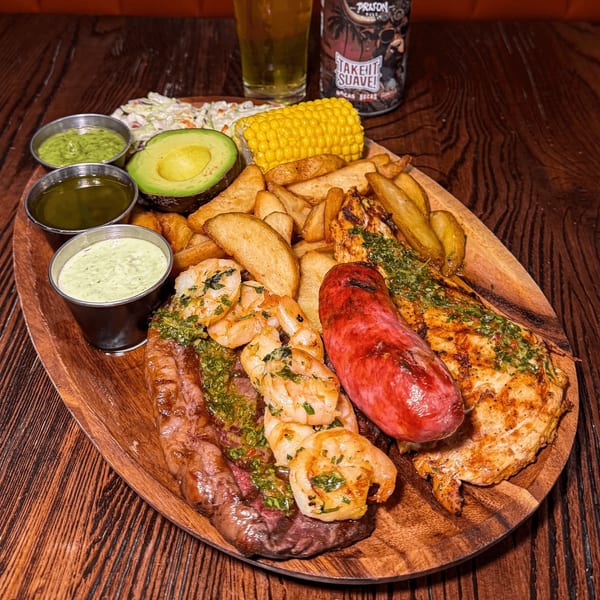 Bocas House mixed grill platter with steak, shrimp, chicken, sausage, fries, corn, avocado, and sauces.