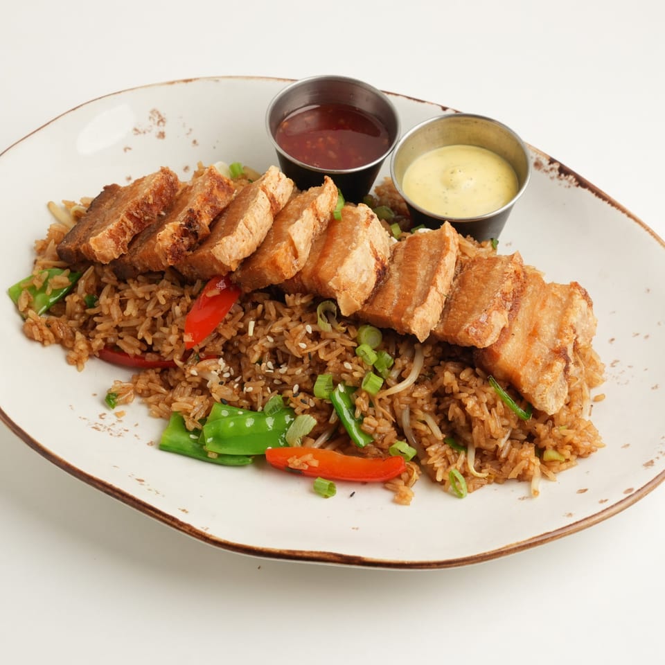 Crispy sliced chicken over seasoned fried rice with peppers, scallions, and sesame seeds, served with red and creamy dipping sauces.