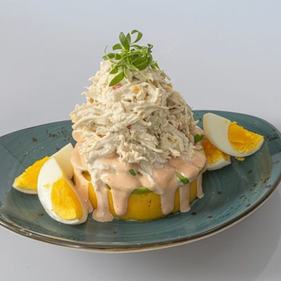 Creamy shredded salad topped with fresh greens, surrounded by orange wedges and egg slices on a blue plate.