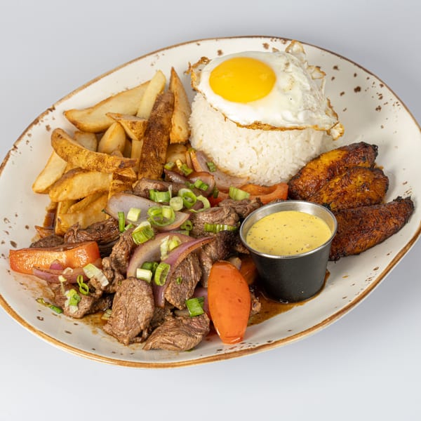 Bocas House Lomo Saltado with steak, fries, rice, fried egg, plantains, and a dipping sauce.